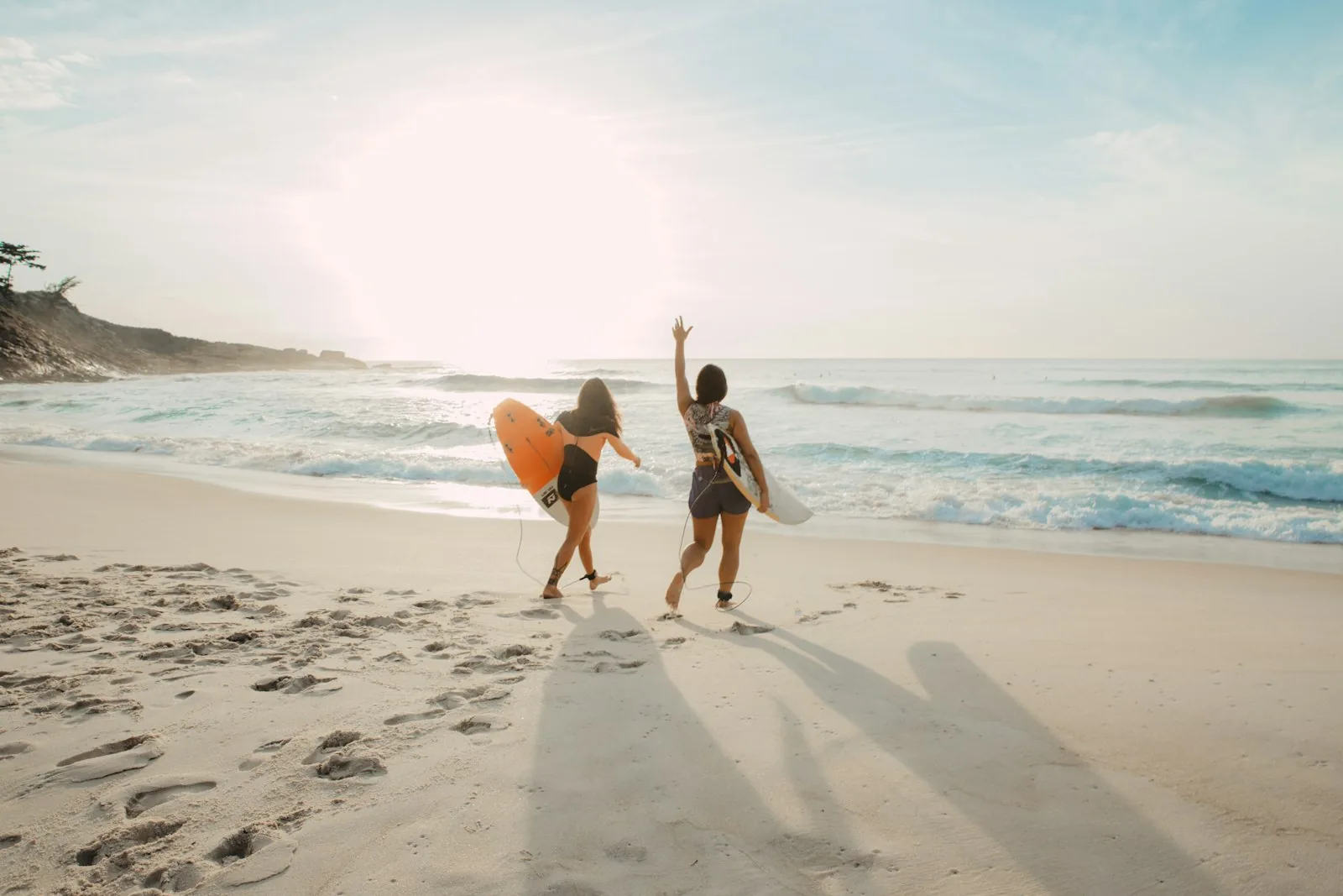 Amiche con la tavola da surf in spiaggia