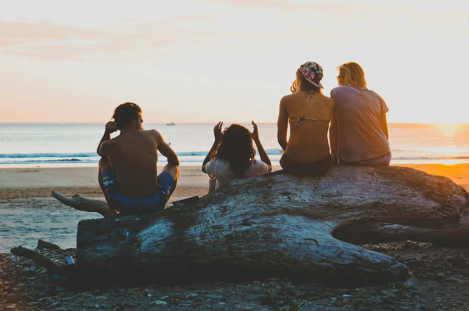 Amici seduti sugli scogli al tramonto